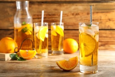 Photo of Delicious refreshing drink with orange slices on wooden table