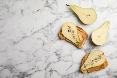 Photo of Tasty toasts with pear, peanut butter and chia seeds on marble background. Space for text