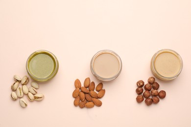 Different types of delicious nut butters and ingredients on beige background, flat lay