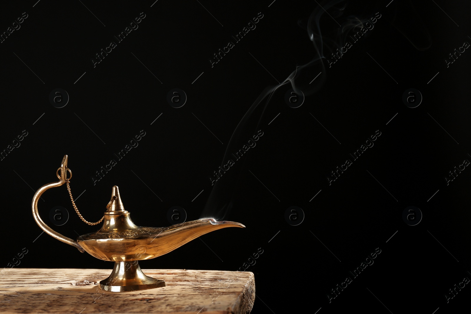 Photo of Aladdin magic lamp on table against black background