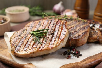 Photo of Delicious grilled pork steaks with herbs and spices on table, closeup