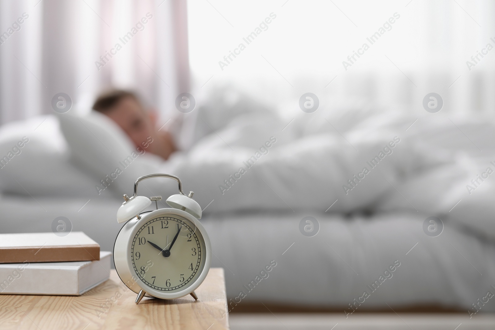 Photo of Man sleeping at home in morning, focus on alarm clock. Space for text