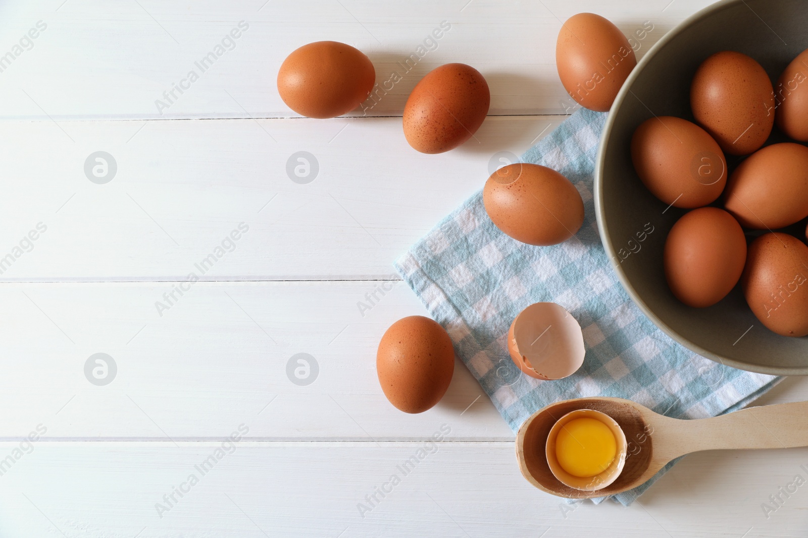 Photo of Cracked and whole chicken eggs on white wooden table, flat lay. Space for text