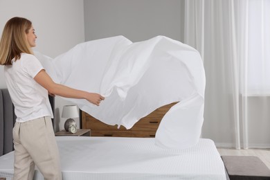Photo of Woman changing bed linens at home. Space for text