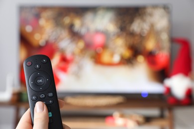 Photo of Woman with remote control watching TV at home, closeup. Space for text