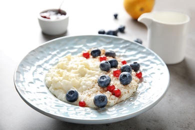 Photo of Creamy rice pudding with red currant and blueberries in bowl served on table