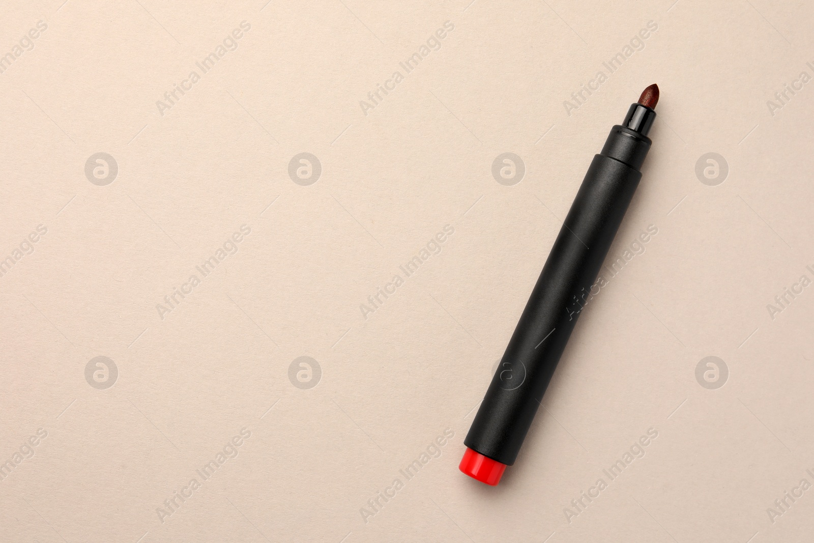 Photo of Bright red marker on beige background, top view. Space for text