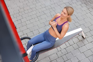 Woman doing abs exercise on bench at outdoor gym, above view