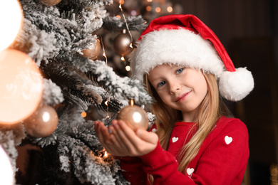 Photo of Cute little child near Christmas tree at home