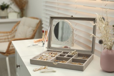 Photo of Elegant jewelry box with beautiful bijouterie on commode indoors