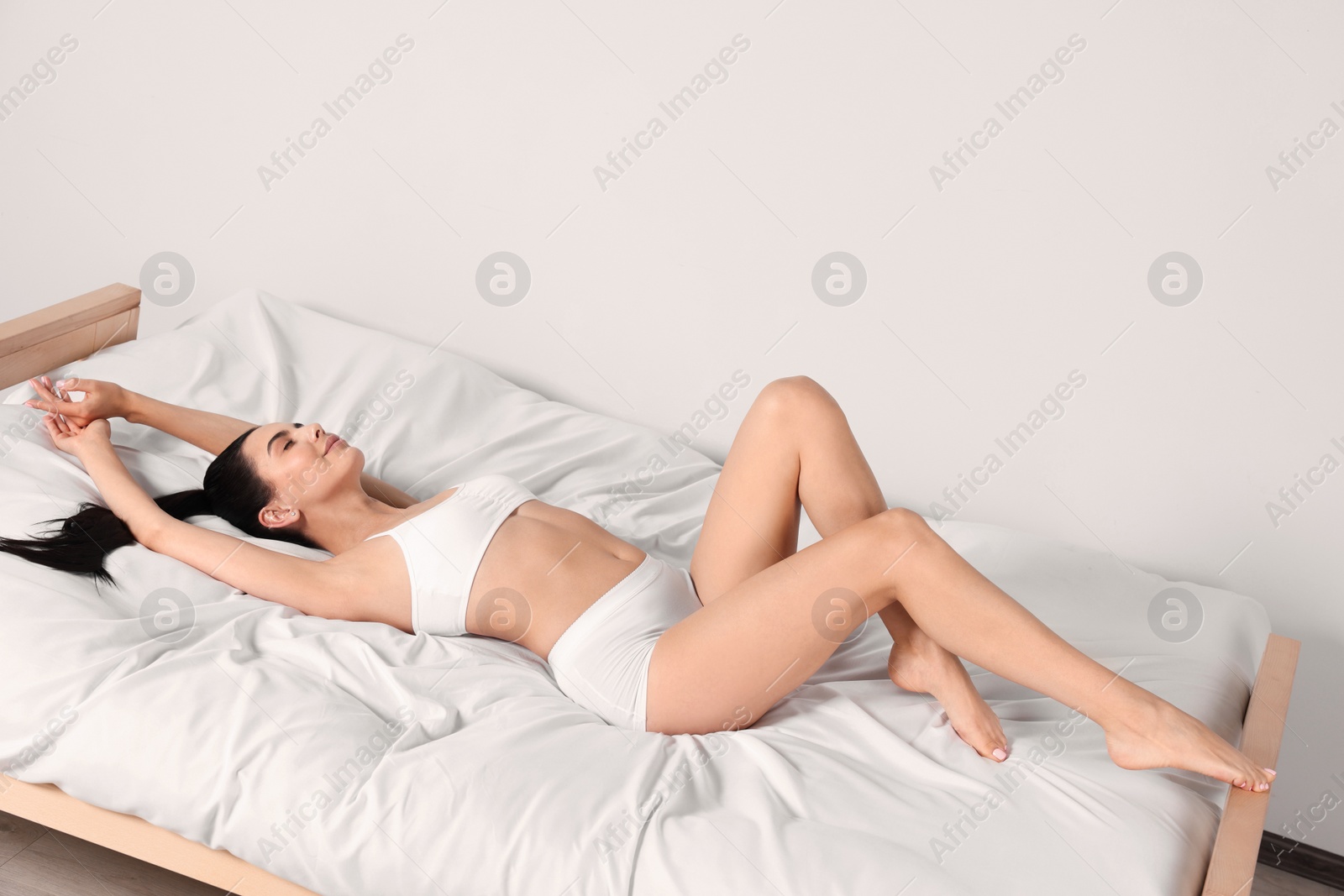 Photo of Young woman with beautiful smooth legs lying on bed at home