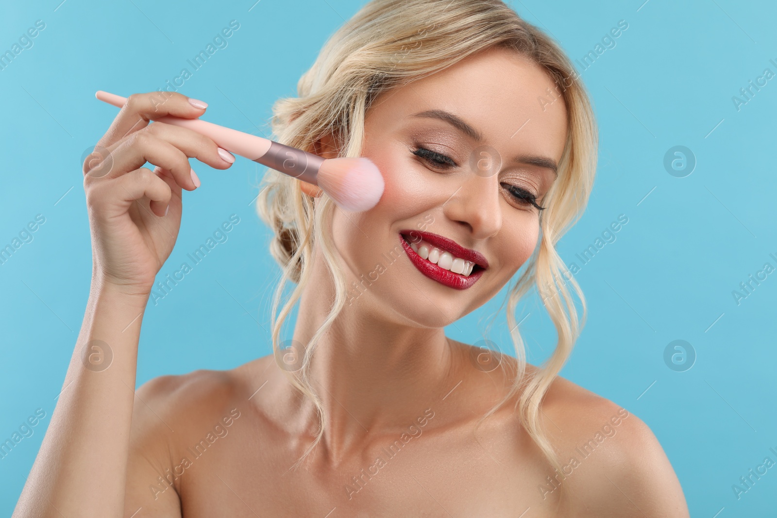 Photo of Beautiful makeup. Smiling woman with brush on light blue background