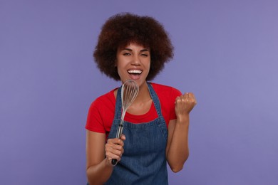 Happy young woman with whisk singing on purple background