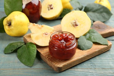 Photo of Delicious quince jam and fruits on light blue wooden table