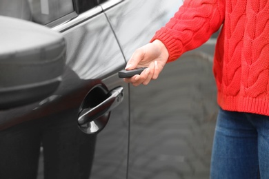 Closeup view of woman opening car door with remote key