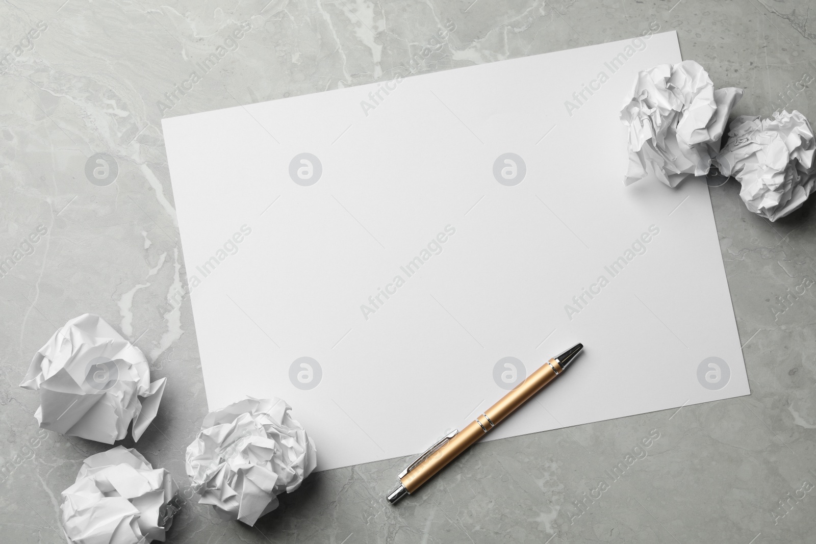Photo of Blank sheet, pen and crumpled paper balls on grey table, flat lay. Space for text