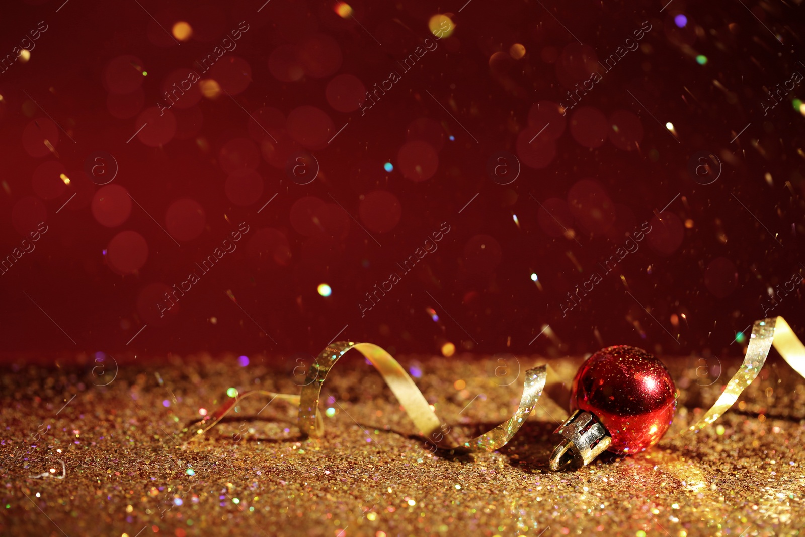 Photo of Golden glitter, Christmas ball and streamer against color background. Space for text