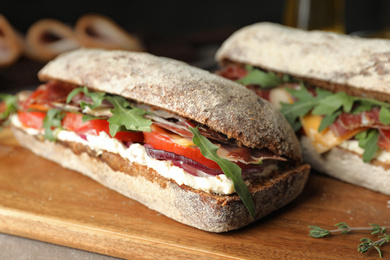 Delicious sandwiches with fresh vegetables and prosciutto on table, closeup