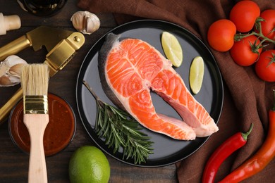 Fresh fish, products and marinade on wooden table, flat lay