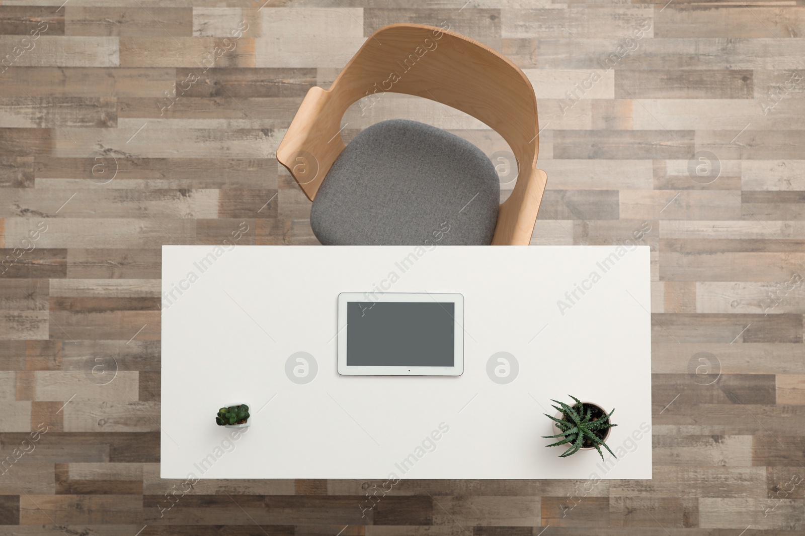 Photo of Plants and computer tablet on wooden table near armchair indoors, top view