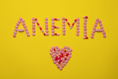 Word Anemia and heart made with pills on yellow background, flat lay