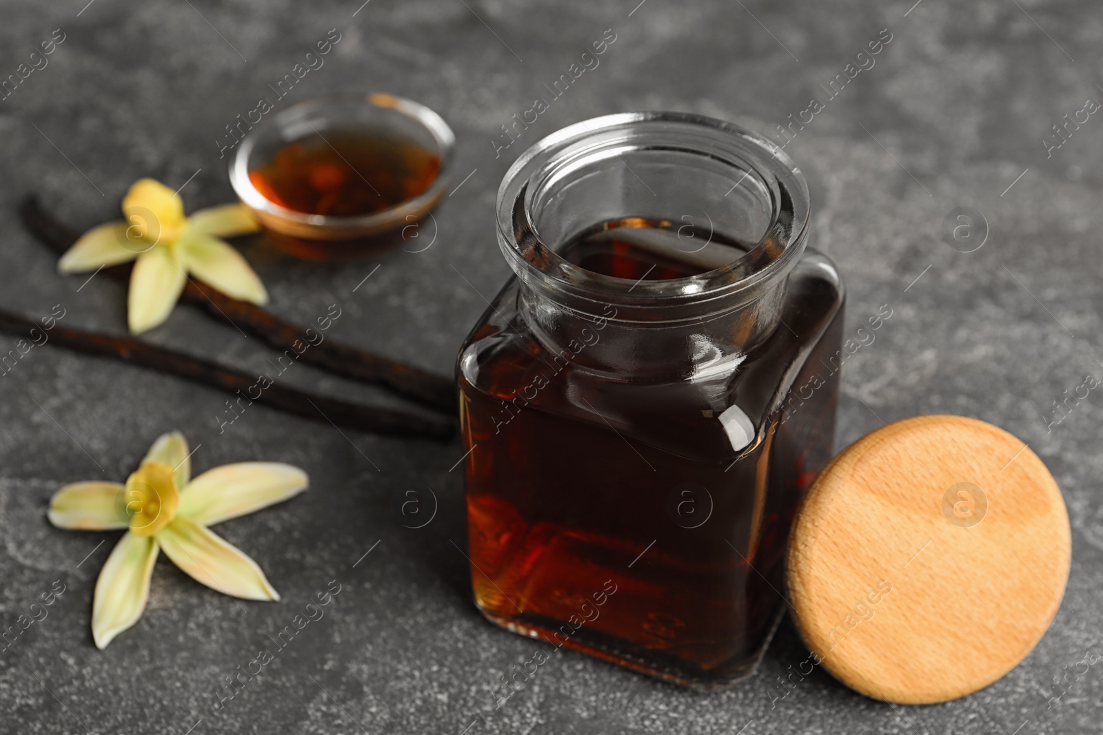 Photo of Aromatic homemade vanilla extract on grey table, closeup