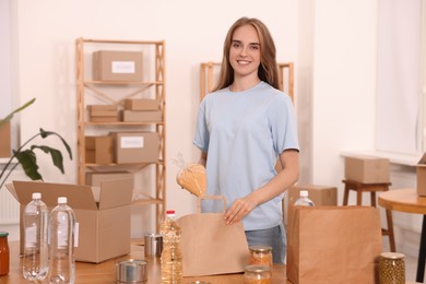 Photo of Portrait of volunteer packing food products at table in warehouse