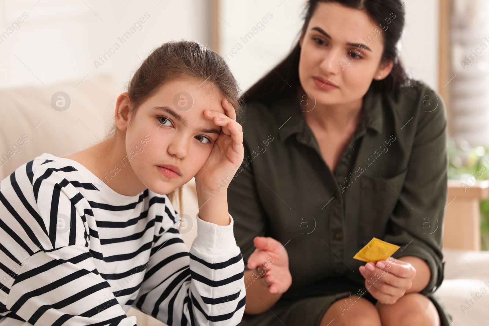 Photo of Mother talking with her teenage daughter about contraception at home. Sex education concept