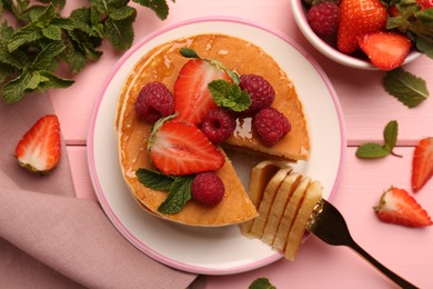 Photo of Eating delicious pancakes with fresh berries and honey at pink wooden table, flat lay