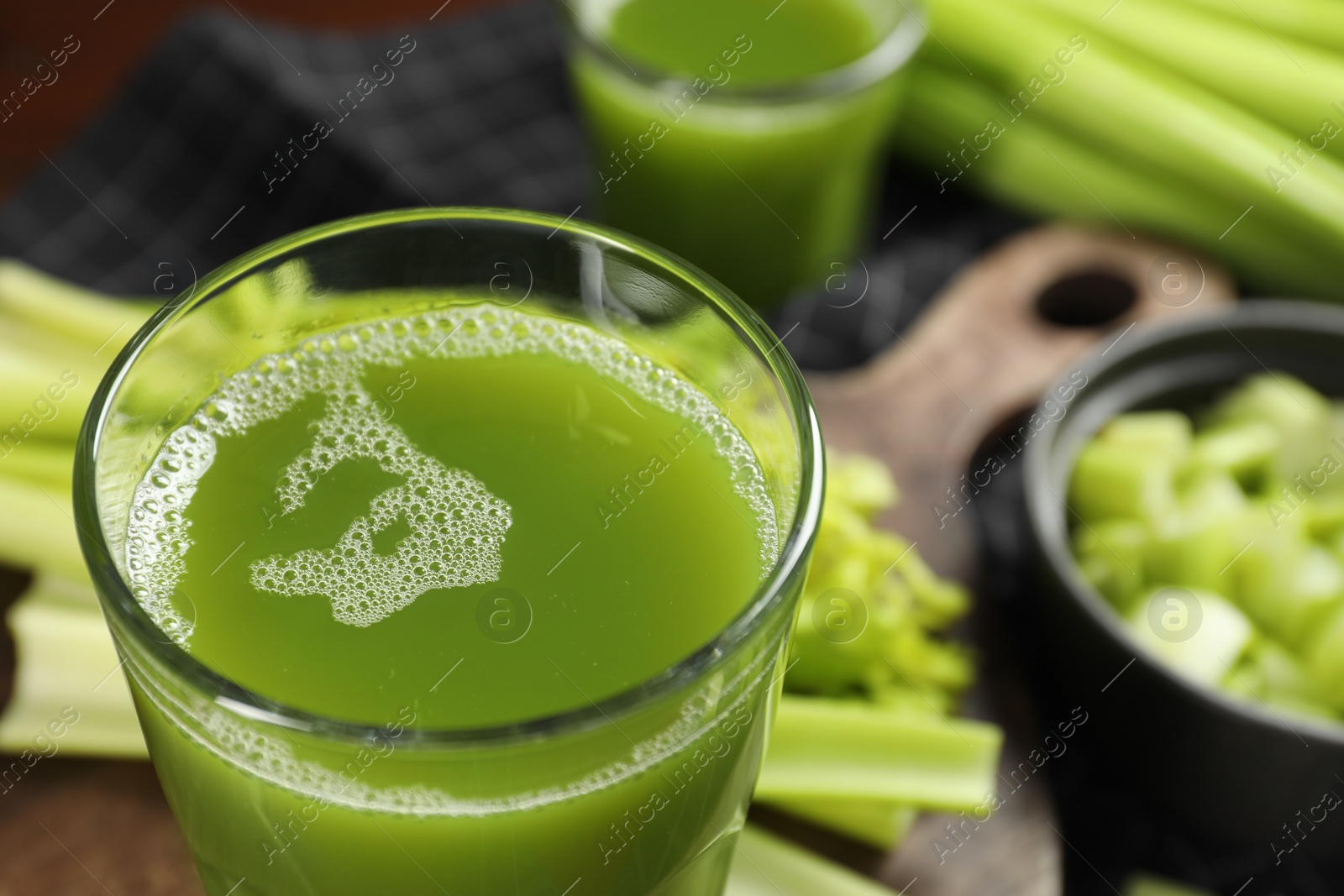 Photo of Glasses of delicious celery juice and vegetables on wooden board, closeup