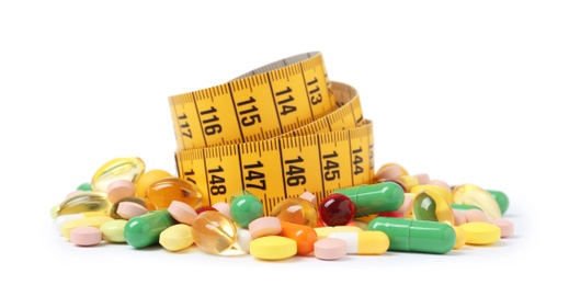 Photo of Weight loss pills and measuring tape on white background