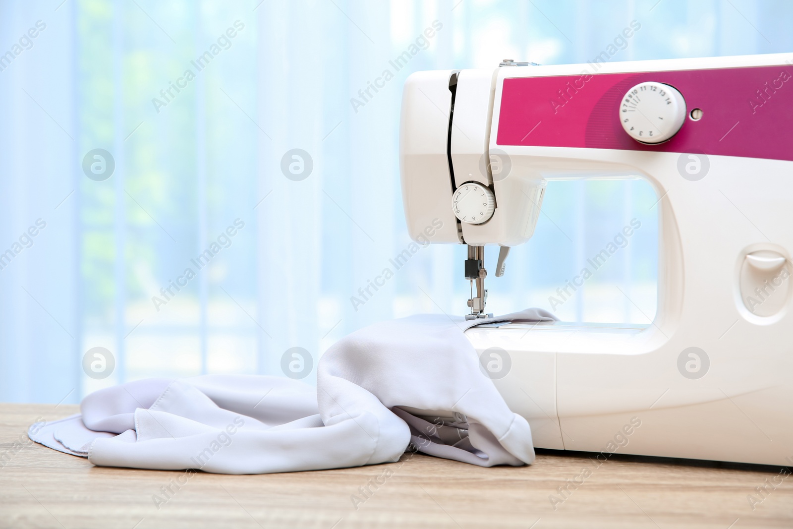 Photo of Sewing machine on table near window indoors