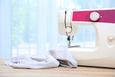 Photo of Sewing machine on table near window indoors