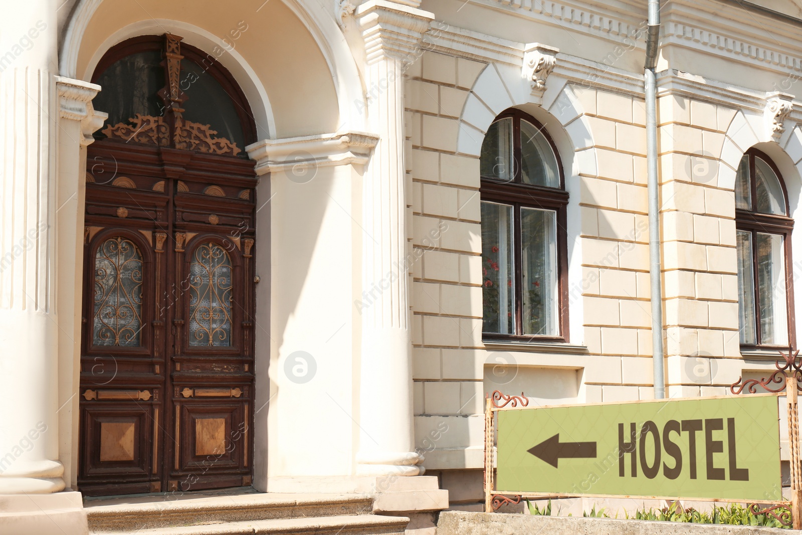 Image of HOSTEL sign board with arrow near old building outdoors