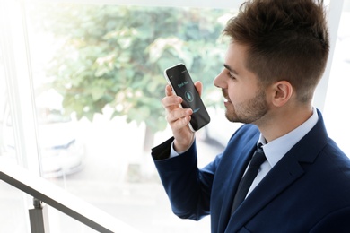Photo of Young man using voice search on smartphone indoors. Space for text