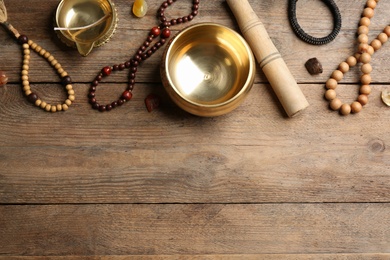 Photo of Flat lay composition with golden singing bowl on wooden table, space for text. Sound healing