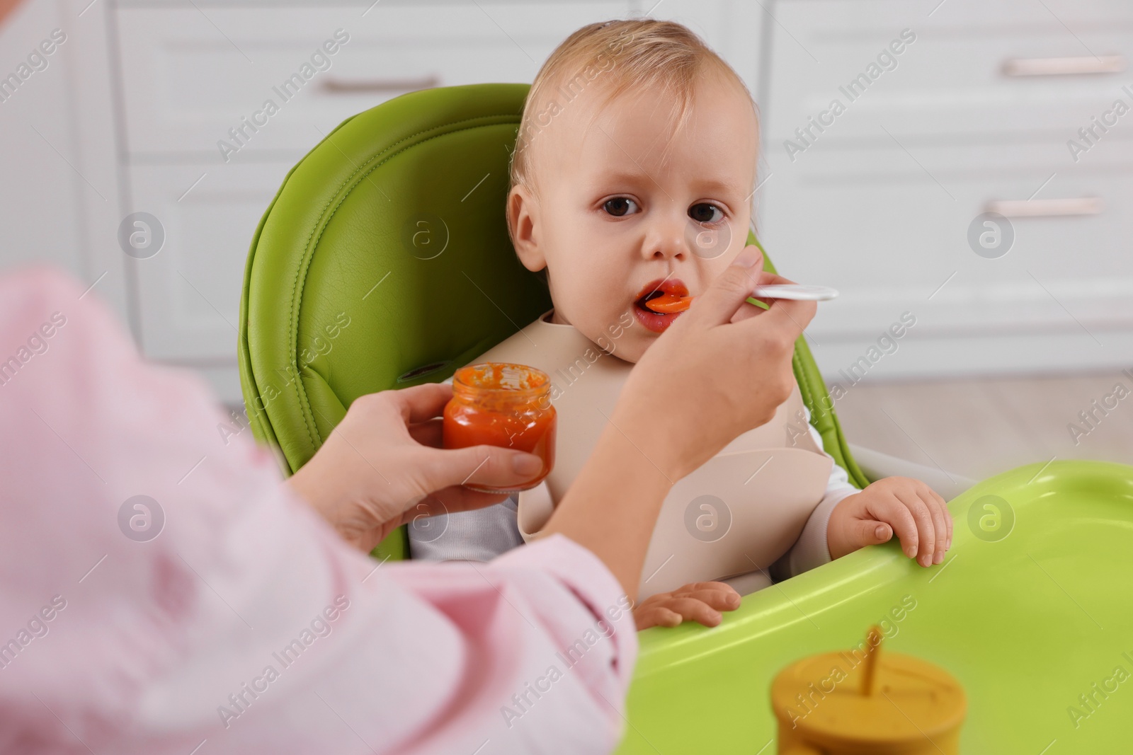 Photo of Mother feeding her cute little baby with healthy food at home