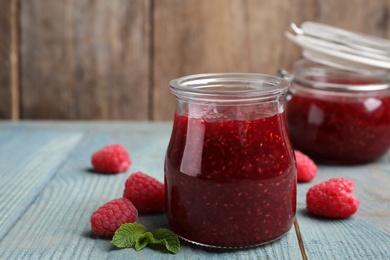 Delicious jam and fresh raspberries on light blue wooden table