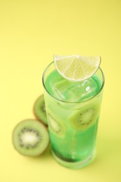 Photo of Glass of refreshing drink and cut kiwi on yellow background, closeup