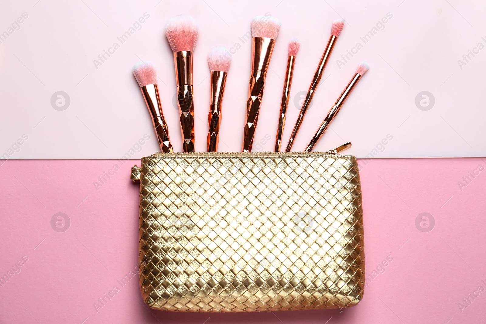 Photo of Bag with different makeup brushes on color background, flat lay