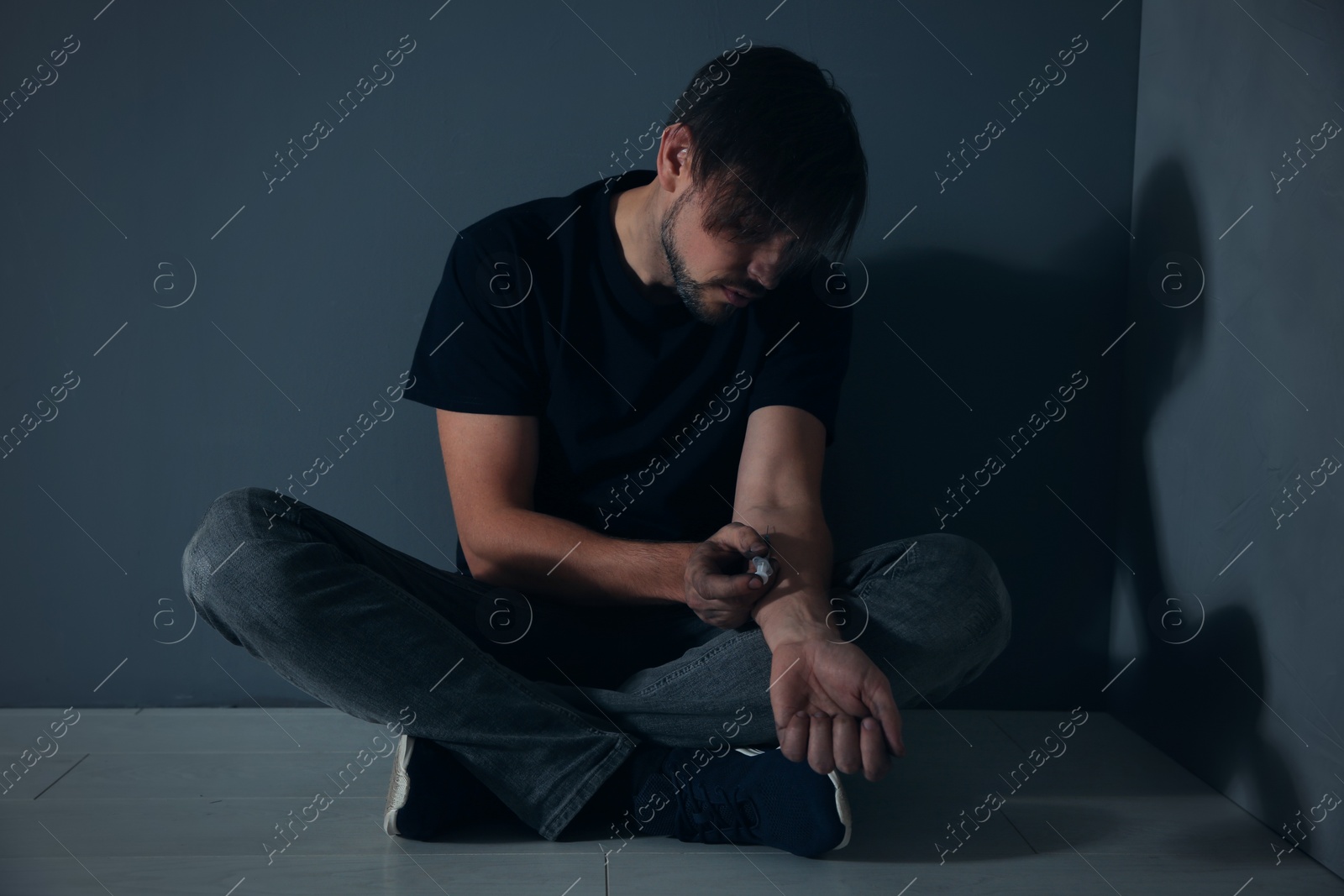 Photo of Male drug addict making injection against grey wall