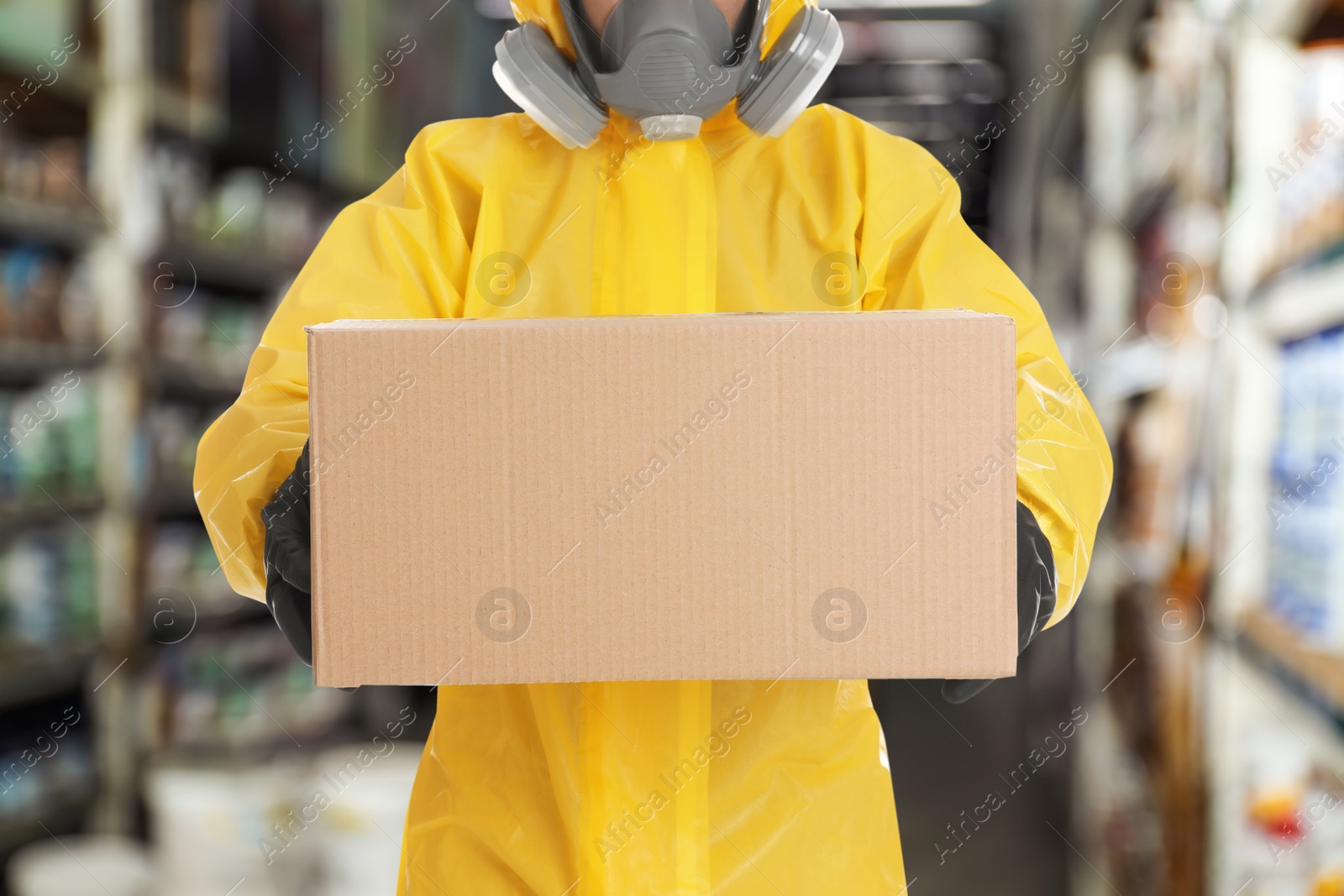 Image of Man wearing chemical protective suit with cardboard box in store, closeup. Wholesale market 