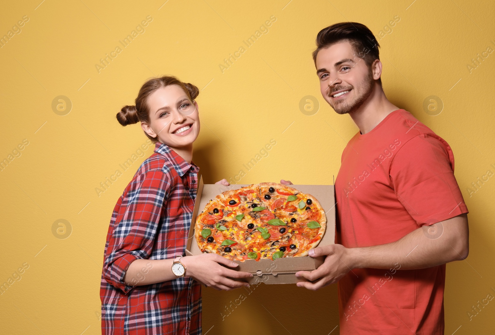 Photo of Attractive young couple with delicious pizza on color background