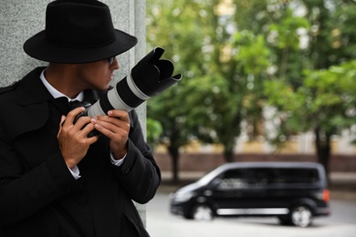 Private detective with modern camera spying on city street