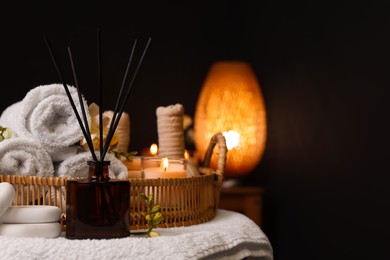 Photo of Aromatic reed air freshener and spa stones on table indoors, space for text