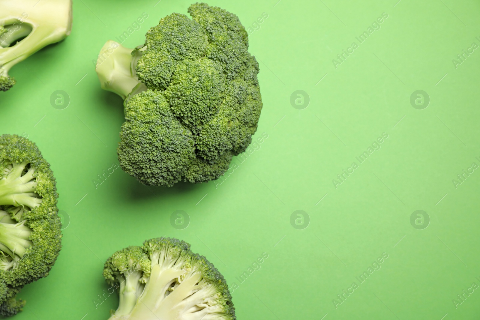 Photo of Fresh broccoli on green background, flat lay. Space for text