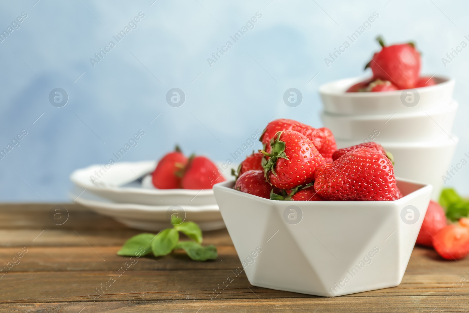 Photo of Bowl with ripe red strawberries on wooden table