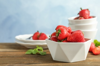 Photo of Bowl with ripe red strawberries on wooden table