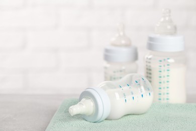 Photo of Feeding bottles with baby formula on light grey table. Space for text