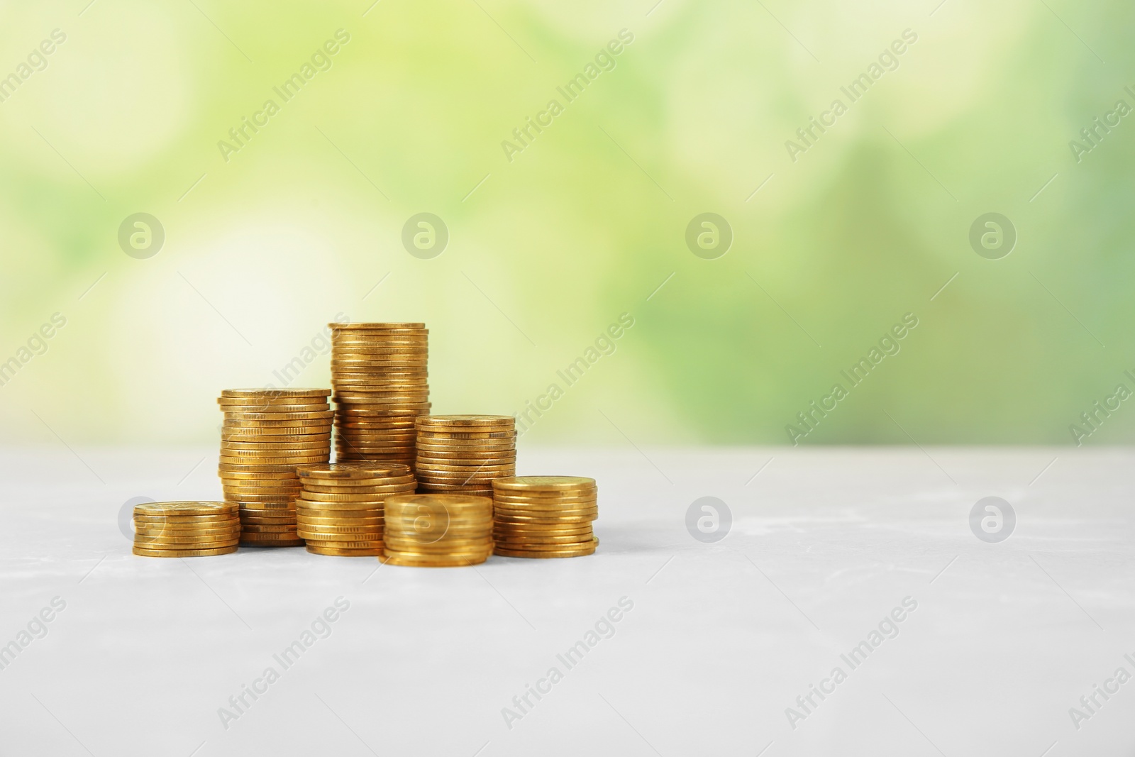 Photo of Stacks of coins on table against blurred background, space for text